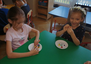 Dziewczynki przy stoliku prezentują swoje prace